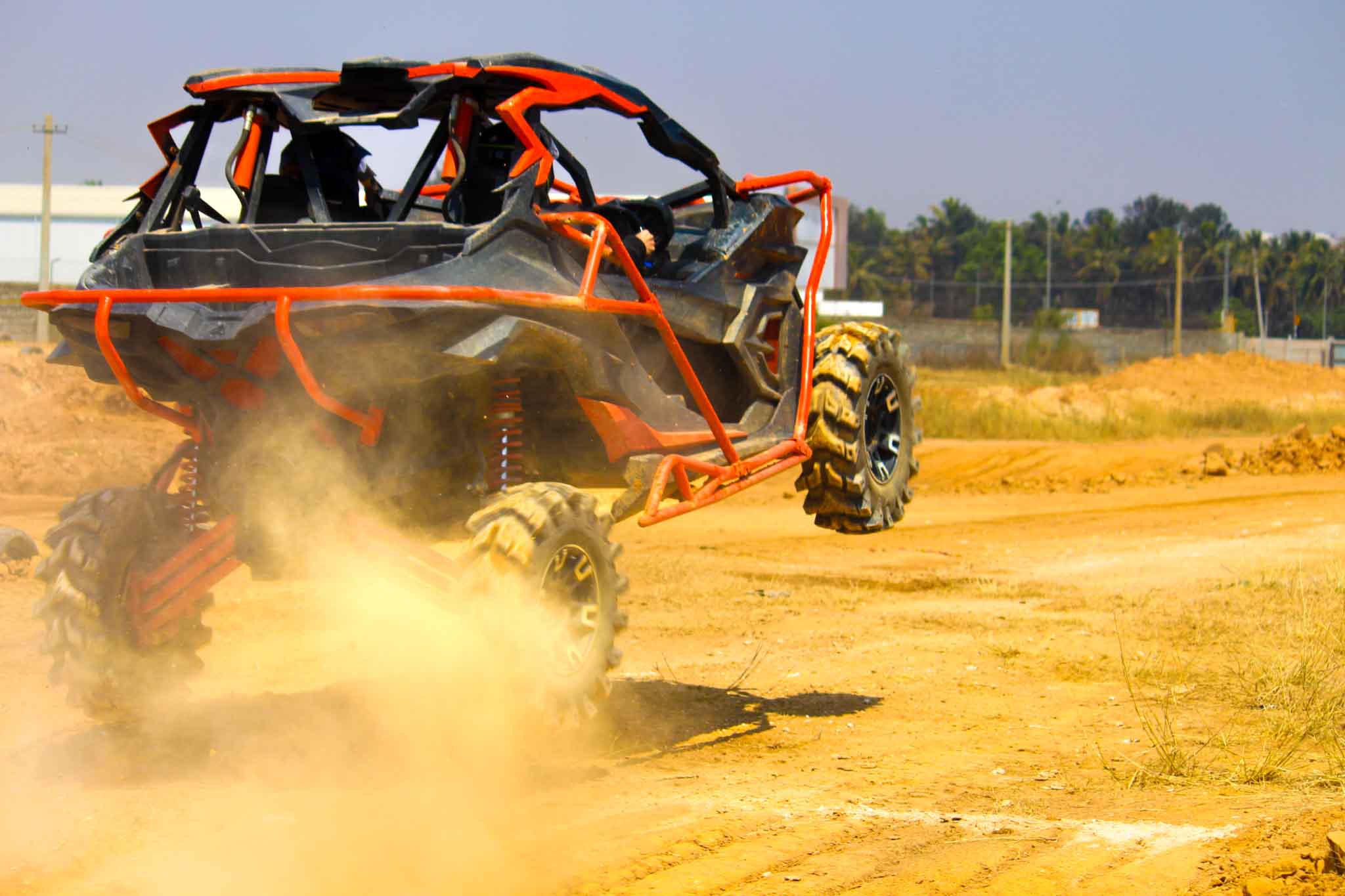 Red off-road ATV airborne and jumping on a dirt track during off-road driving event.